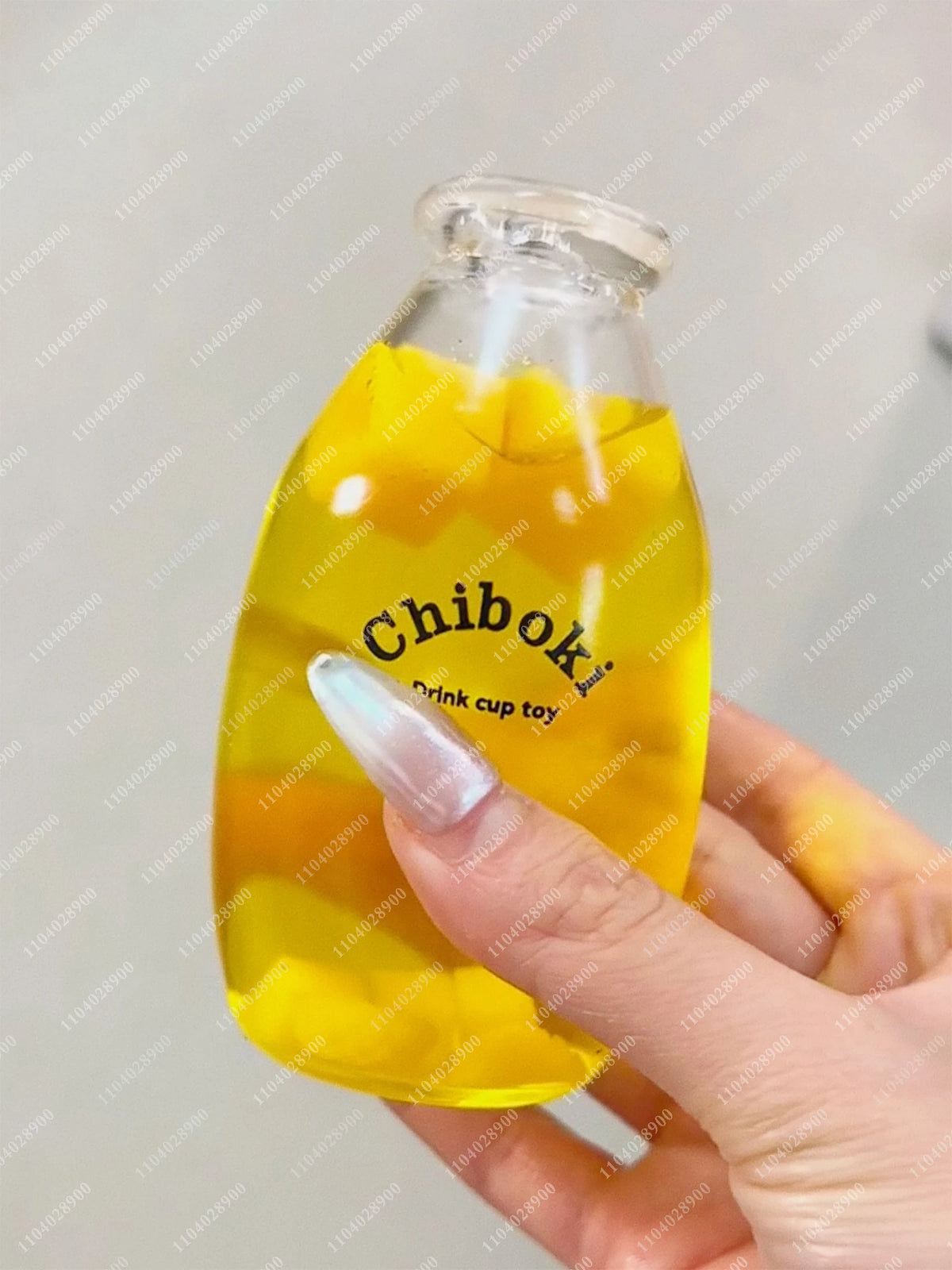 A hand holds a yellow squishy milk bottle stress ball with the Chibok brand label.