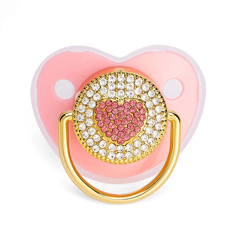 A rose gold crystal bling pacifier with a heart design and a gold ring for newborns.