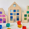 A collection of wooden building blocks in various shades of blue, green, and pink are arranged against a white background.