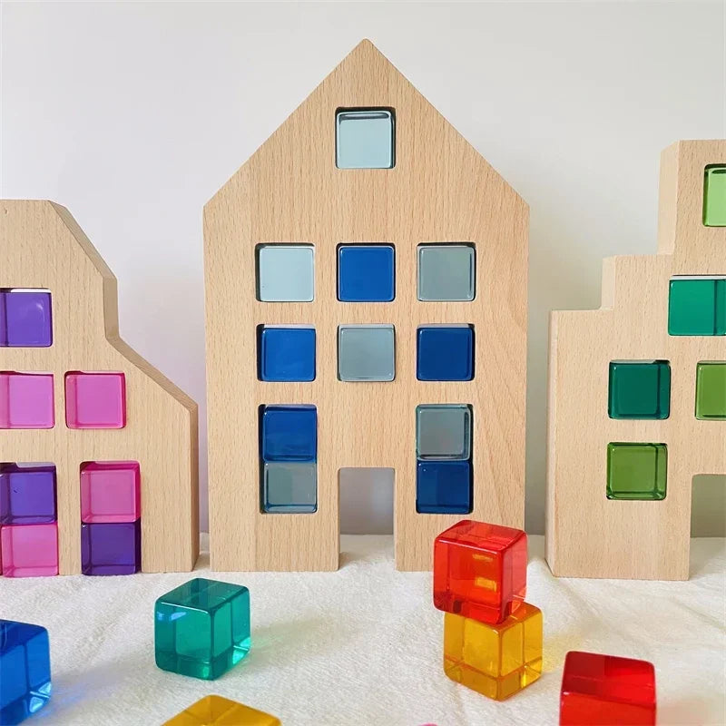A collection of wooden building blocks in various shades of blue, green, and pink are arranged against a white background.