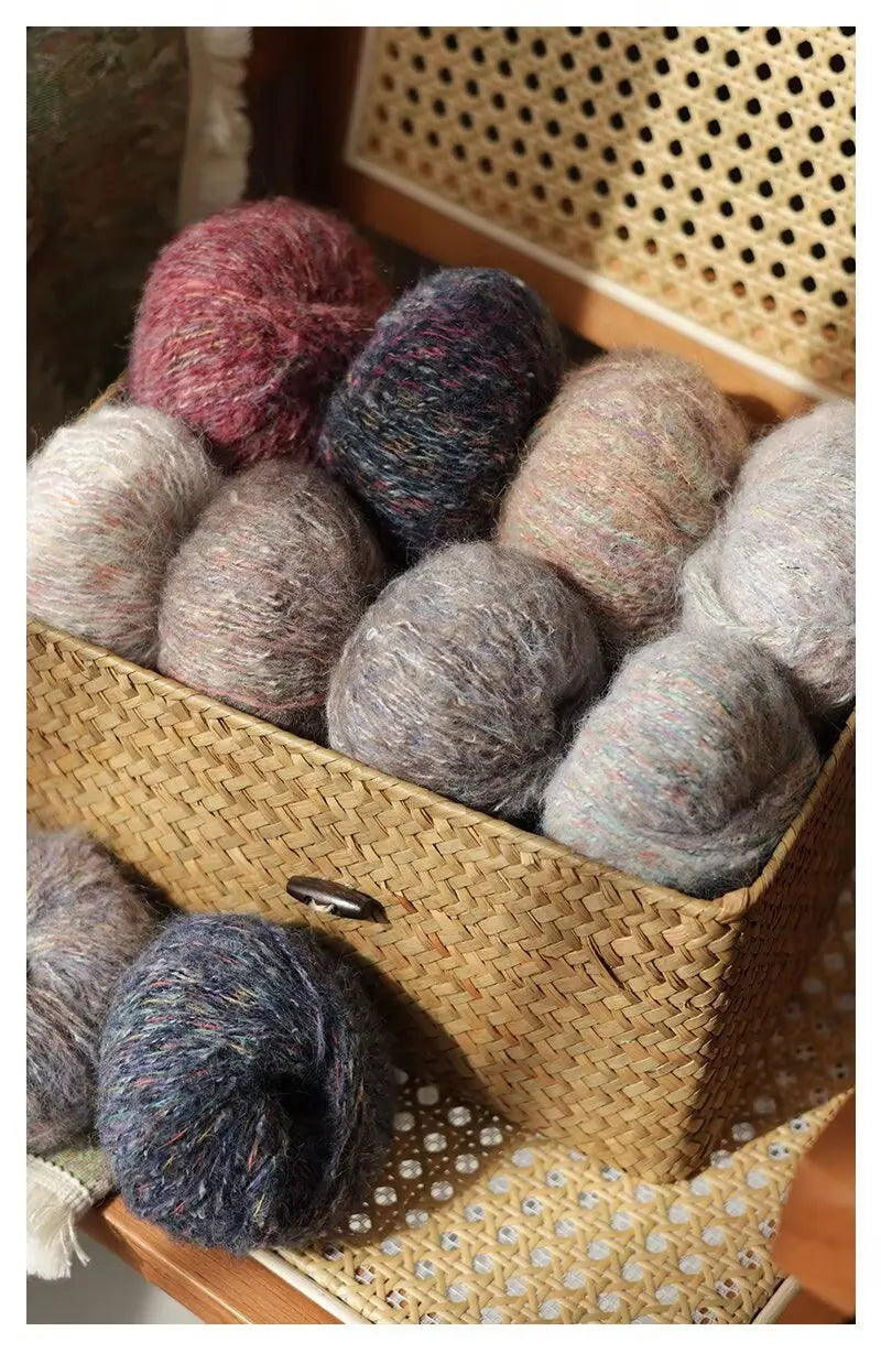 A collection of multicolored soft alpaca blend yarn skeins in various shades and textures stored in a woven basket.