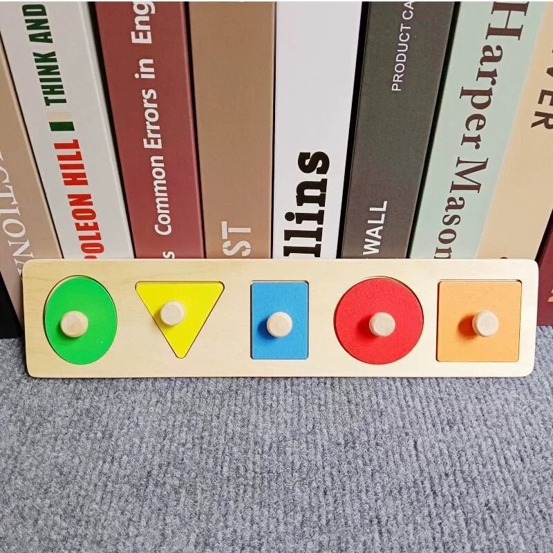 A wooden shape and color sorter puzzle with five colored shapes and wooden pegs on a gray surface.