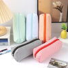 A collection of striped canvas pencil cases in various colors and sizes, including green, blue, orange, and red.