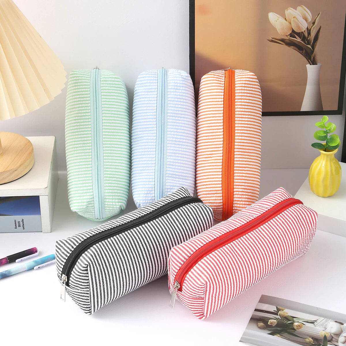 A collection of striped canvas pencil cases in various colors and sizes, including green, blue, orange, and red.