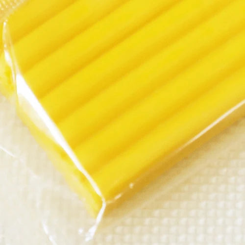 A close-up of a rectangular block of bright yellow polymer clay modeling material.
