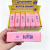 A hand holds a pink butter squishy toy next to its packaging box.