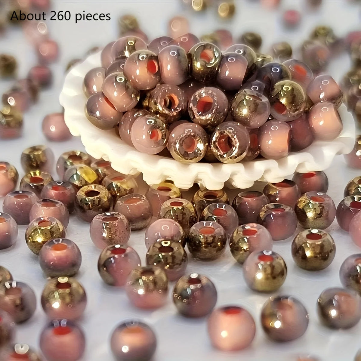 A pile of round, iridescent beads in shades of pink and gold for jewelry making.