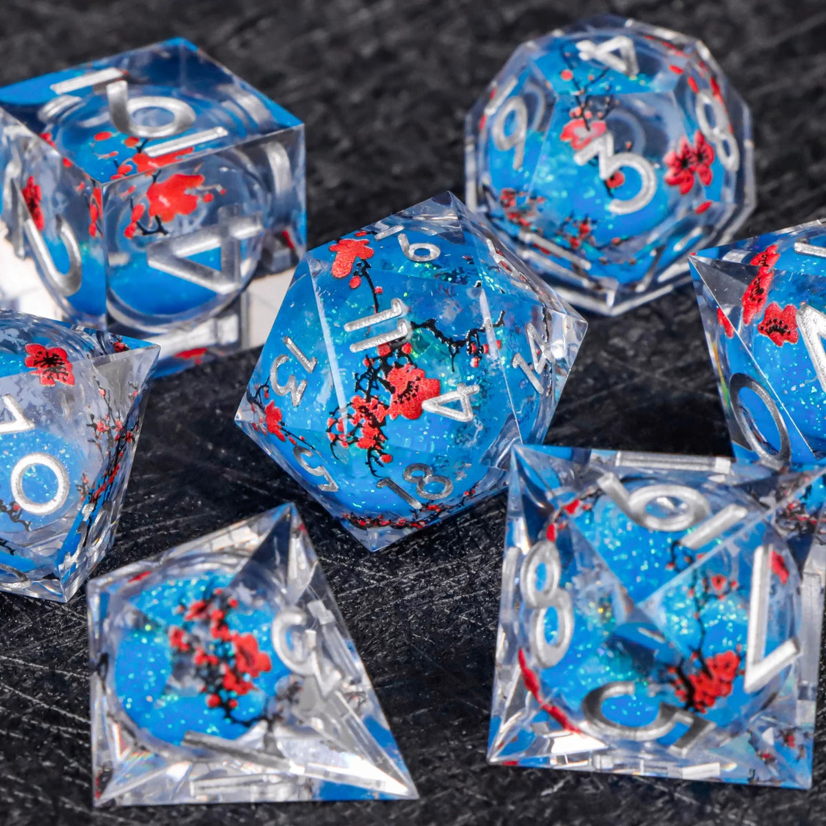 A collection of translucent blue dice with red markings scattered on a dark surface.