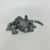 A highly detailed gray figurine of an articulated Sphynx cat with piercing blue eyes.