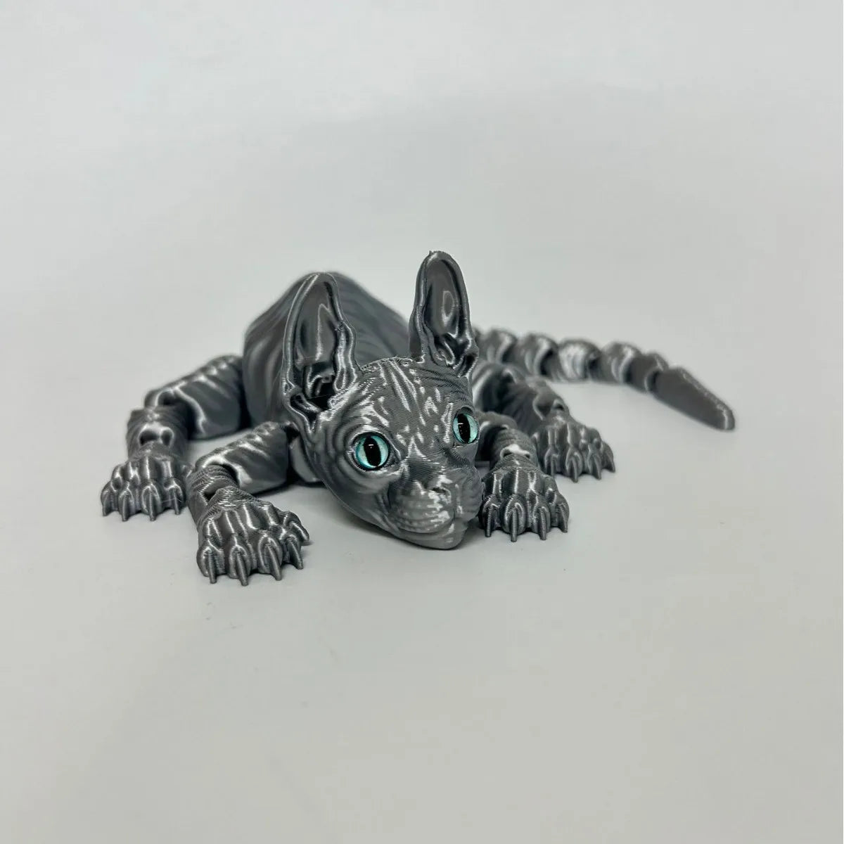 A highly detailed gray figurine of an articulated Sphynx cat with piercing blue eyes.