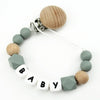 A personalized name pacifier clip featuring wooden and silicone teething beads on a white cord.