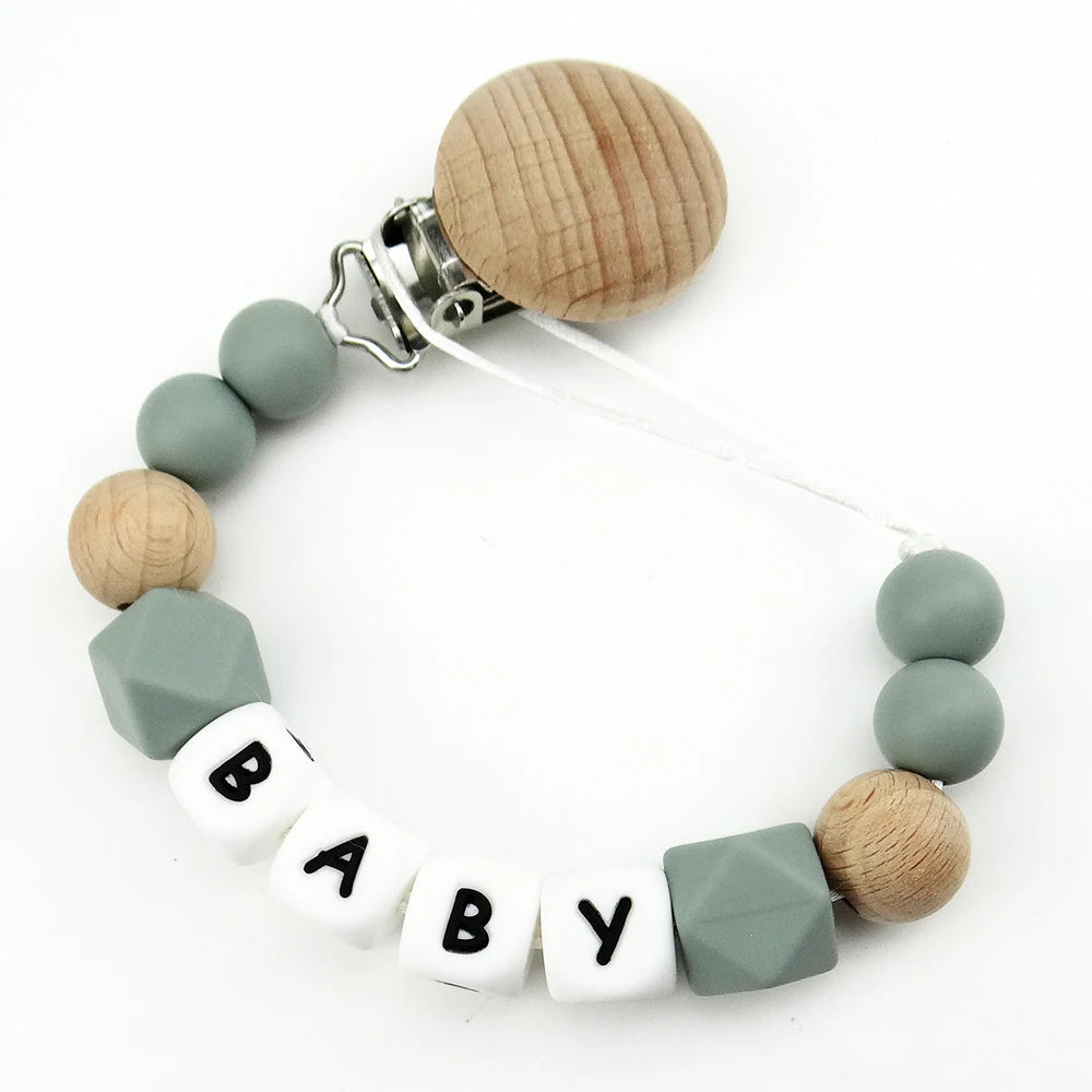 A personalized name pacifier clip featuring wooden and silicone teething beads on a white cord.