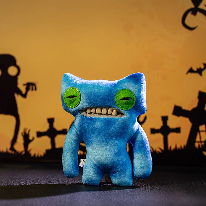 A blue plush monster doll with large teeth and green eyes against a dark background.