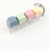 A clear acrylic keychain featuring four colorful, pastel-colored clicky key buttons attached to a metal ring.