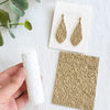 Two gold-toned floral texture rollers for polymer clay and crafting displayed on a white surface.