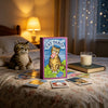 A box of Cat Tarot cards resting on a bed with soft lighting and other tarot cards scattered nearby.