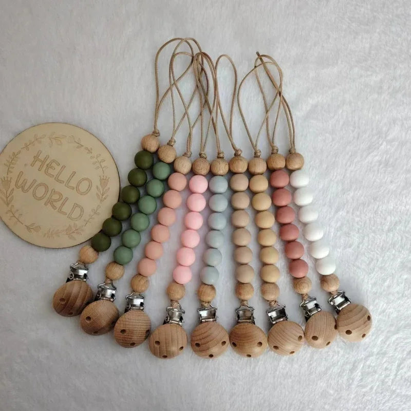 A collection of wooden beads on leather cords with silicone clips, featuring pastel green, pink, and white colors.