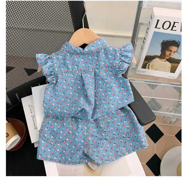 A blue floral print girls' sleeveless shirt and shorts set displayed on a hanger.