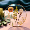 A clear glass circle holds dried flowers and greenery, showcasing natural elements for jewelry making.