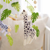 A wooden felt giraffe mobile with green leaves and natural wood beads hanging in a nursery setting.