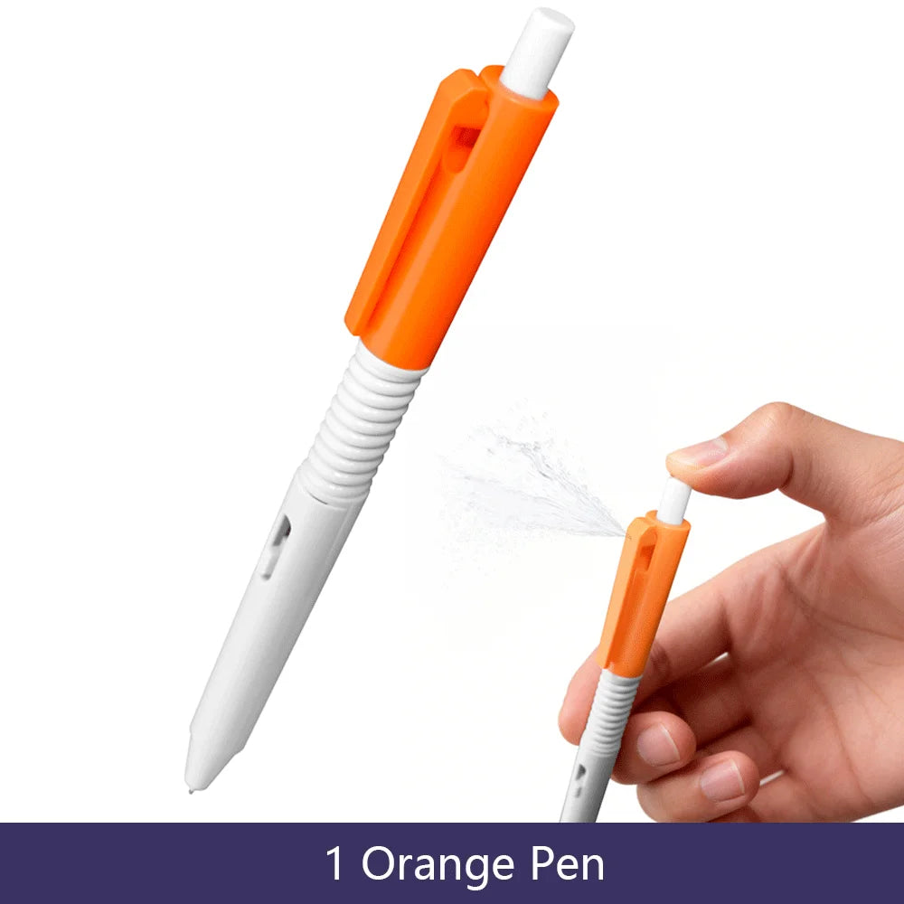 An orange ballpoint pen is shown being used to spray a fine mist of water onto a hand.
