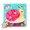 A wooden puzzle game featuring a yellow and green creature and a pink striped circle on a teal background.