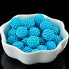 A white bowl filled with bright blue acrylic pearl beads for jewelry making