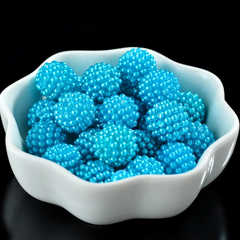 A white bowl filled with bright blue acrylic pearl beads for jewelry making