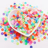 A pile of colorful polymer clay sprinkles in various shades of pink, blue, green, and orange scattered on a white surface.