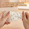 Hands hold a clear, round, tear-resistant silicone stress relief ball on a wooden surface.