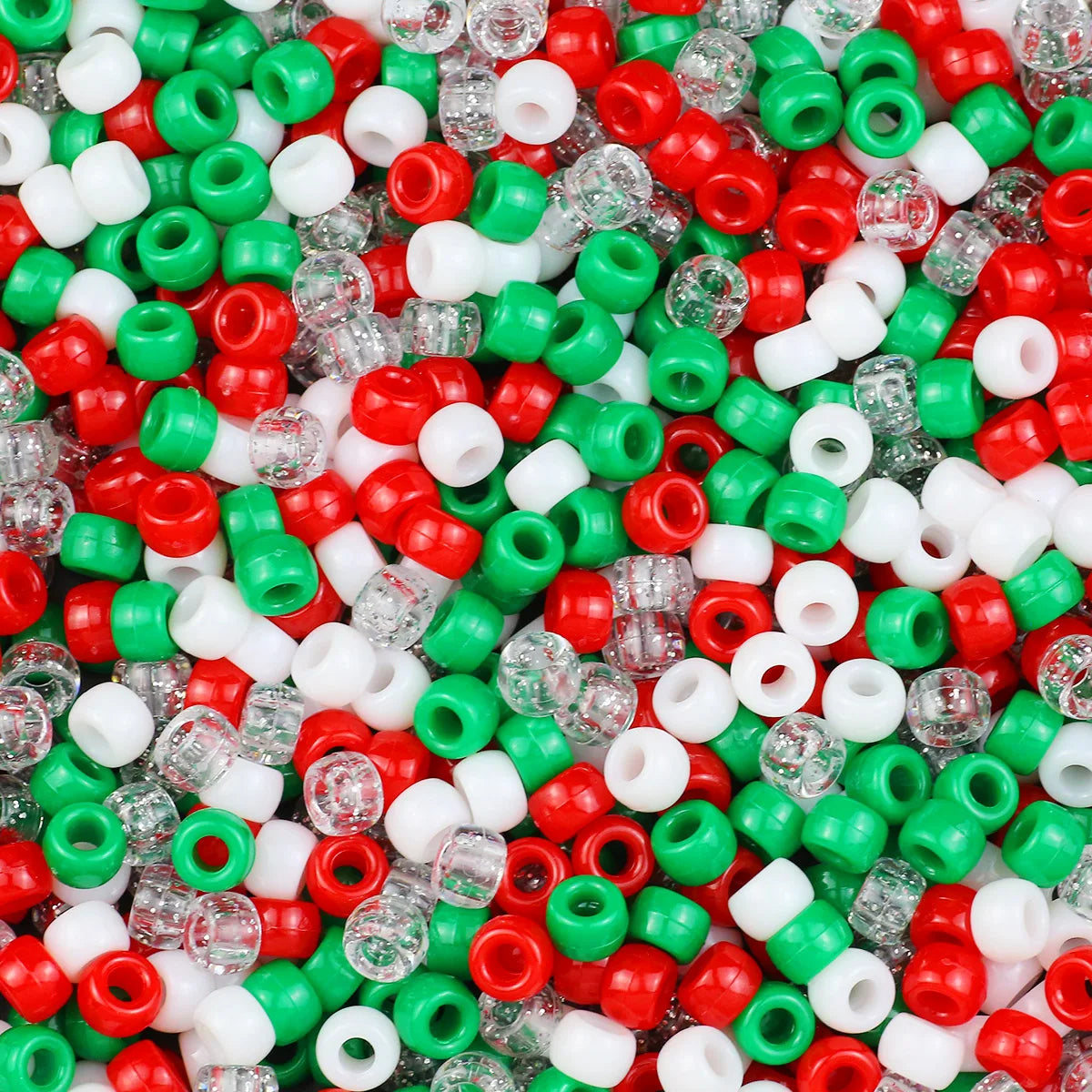 A close-up view of small, solid color pony beads in red, green, and white scattered on a surface.