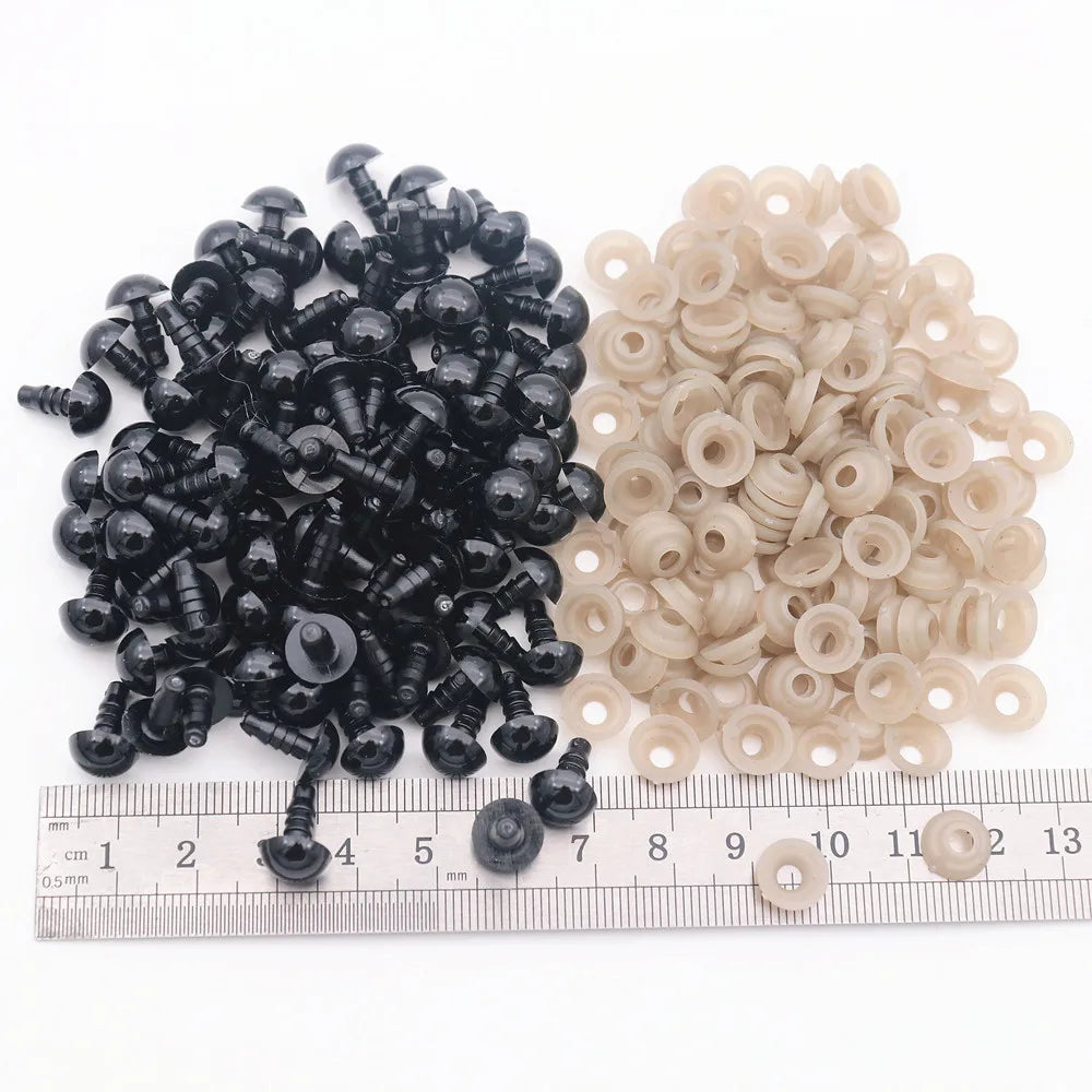 A collection of black and beige plastic safety eyes for amigurumi with locking washers displayed on a ruler.