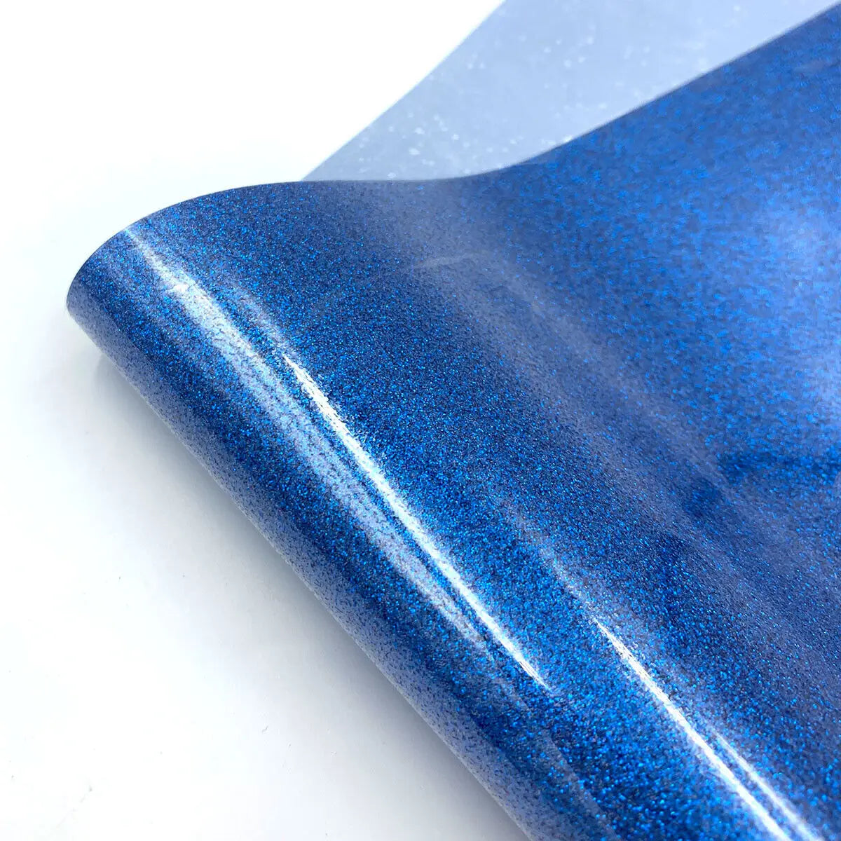 Close-up of a blue glitter holographic heat transfer vinyl sheet rolled up.