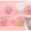 A collection of colorful rainbow squishy stress relief balls resting on a pink surface.