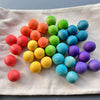 A collection of colorful, spherical sensory music trees with marble run components arranged on a white cloth.