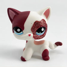 A small, stylized cat figure with white and maroon markings and large eyes.