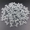 A pile of 20 clear acrylic bow beads for jewelry making scattered on a dark surface.