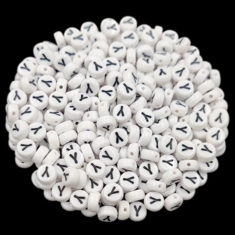 A pile of small white acrylic alphabet letter beads for jewelry making