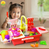 A child is playing with a red and pink electric kitchen sink toy set featuring running water and play food.