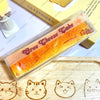 A clear plastic package of Oreo Cheese Take butter stick squishy toy resting on a wooden surface.