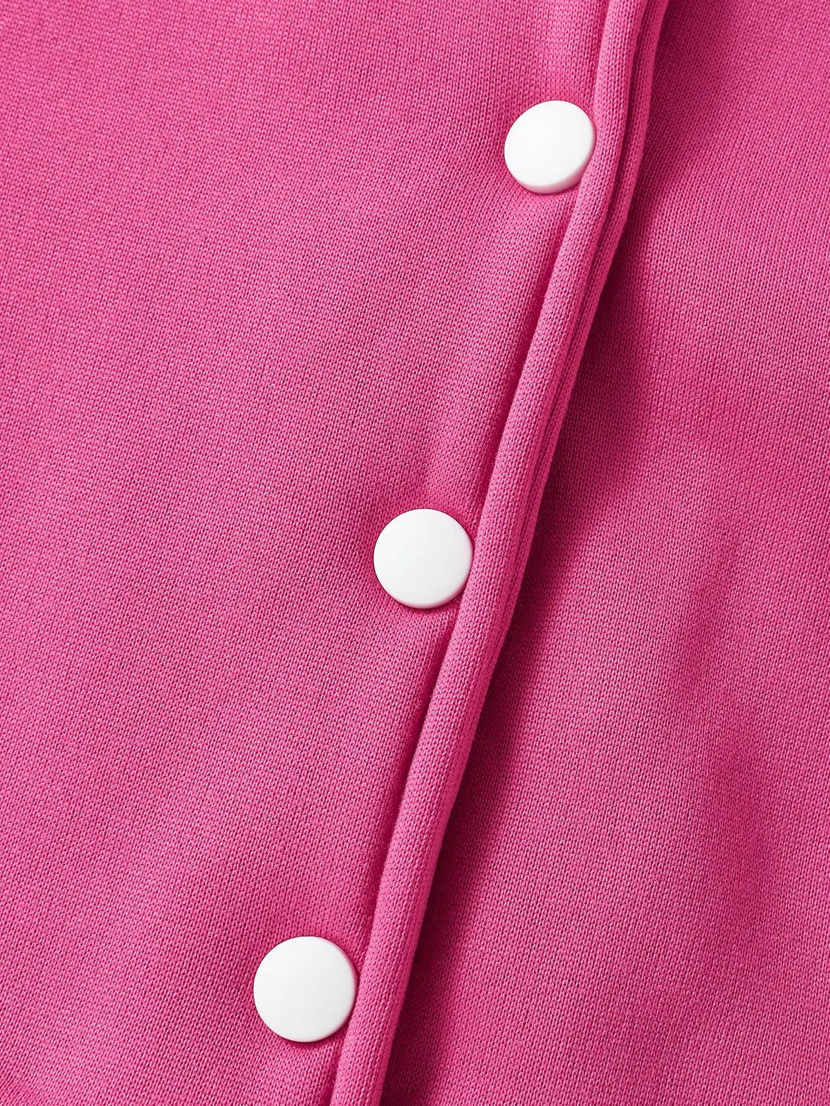 Close-up of a bright pink knitted cardigan with white buttons on the front