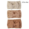 A set of three beige and brown knitted baby headbands with bows