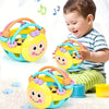 A baby is holding a yellow sensory catch ball rattle toy with purple accents and a blue ring.