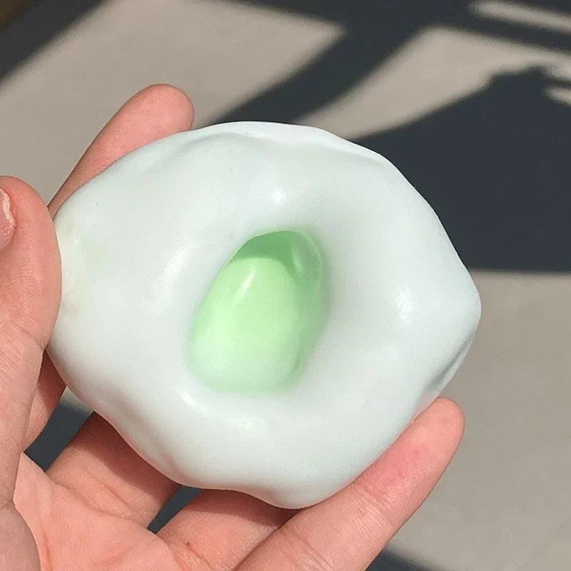 A hand holds a translucent, pale green squishy stress relief ball with a visible inner core.