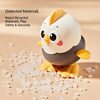 A white and gray wind-up chick toy is shown with small clear plastic pieces scattered around it.