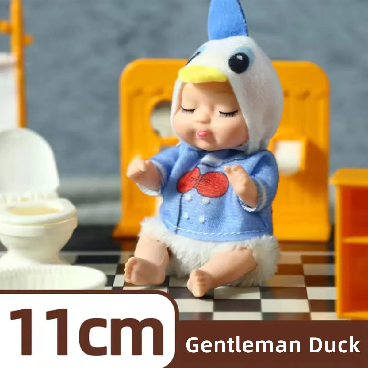 A small figurine of a Gentleman Duck baby doll with white fur and blue clothing is shown on a surface.