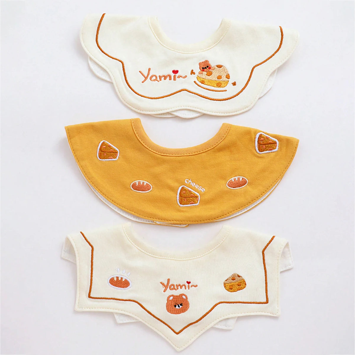 Set of three baby waterproof drool bibs featuring cute animal designs in cream and mustard yellow.