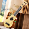 A light wood toy guitar is displayed next to a wooden box, showing its size and detail.