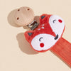 An orange fox-shaped pacifier holder with a wooden top and metal clip against a light background.