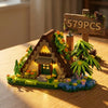 A miniature wooden cabin building block set featuring a greenhouse, chimney, and a signpost with the text 579PCS.